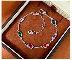 Close-up of rainbow gemstone bracelet with mixed cut stones and heart charm in a box