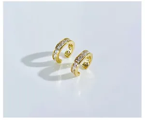 Macro shot of gold-plated C-shaped ear cuffs with a row of white square-cut zircons