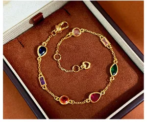Detailed view of a gold-plated bracelet with multi-color gems in a brown velvet box