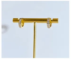 Close-up of gold-plated crescent earrings with square-cut cubic zirconia on a stand