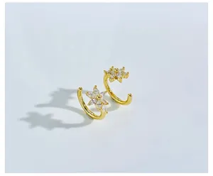 Close-up of golden C-shaped flower earrings with marquise-cut crystal petals