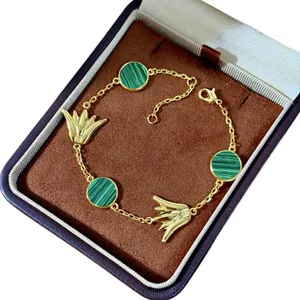 Goldenes Blumenarmband mit Malachit-Inlays und Quasten auf braunem Schmuckkästchen