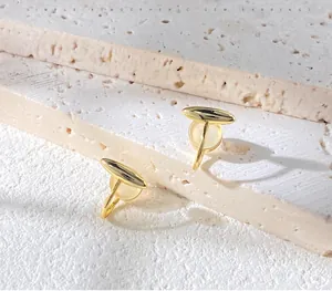 Detailed macro view of minimalist golden cat's eye earrings on natural stone texture