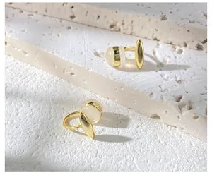 Detail of asymmetrical gold ear clips with opals on minimalist stone background