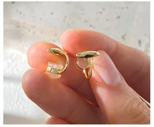 Macro detail of asymmetric cat eye stone earring clip with polished golden metallic finish
