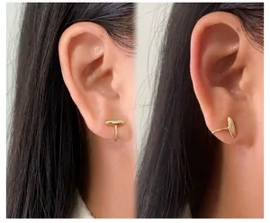 Detailed view of asymmetric gold-plated cat eye stone ear clips shown on a female model