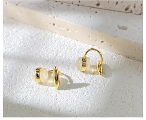 Detail of gold U-shaped opal clip earrings displayed on natural travertine stone