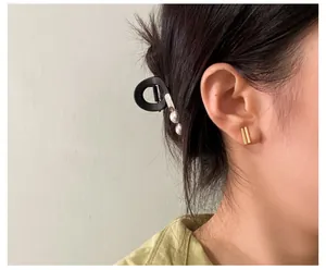 Detail of minimalist gold rectangular ear clip on model with elegant matte finish