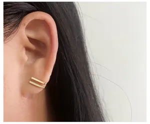 Macro detail of golden geometric double-bar ear cuff clip on model ear