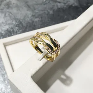 Macro detail of gold-plated intertwined U-shaped ring with pavé diamond setting