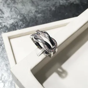 Silver infinity interlocking U-shape ring with pavé diamonds on a white gift box