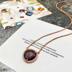Gros plan d'un collier en or rose avec une pierre violette taillée et cristaux