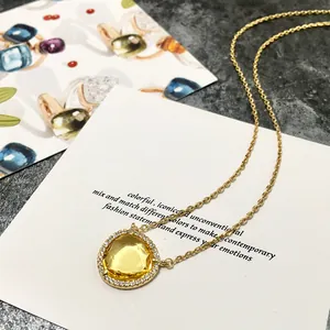 Détail d'un collier doré avec cristal jaune en forme de poire et sertissage micro-pavé