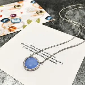 Vue macro du pendentif en cristal bleu clair avec halo de diamants pavé sur chaîne argent