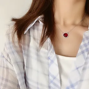 Gros plan d'un collier avec pierre rouge et pavage de cristaux porté par un mannequin