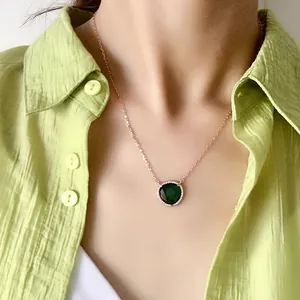 Élégant collier en or rose avec un pendentif rond en cristal vert foncé et un halo de zircons