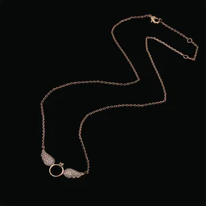 Elegant rose gold wing necklace with pavé crystal ring pendant on black background
