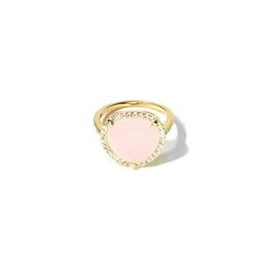 Gros plan d'une bague dorée avec une grande pierre rose en cœur et pavé de cristaux