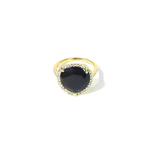 Gros plan détaillé d'une bague cocktail dorée avec une grande pierre noire et cristaux