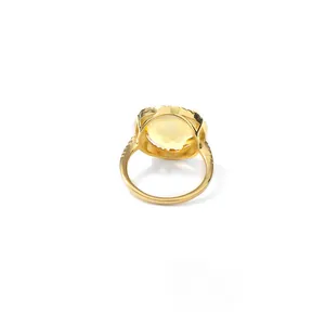 Détail d'une bague vintage en or avec une grande pierre jaune et des accents pavés