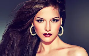 Close-up of model wearing large gold hoop earrings with pavé set sparkling diamonds