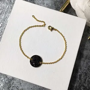 Gros plan d'un bracelet doré avec un pendentif rond serti de cristaux noirs brillants