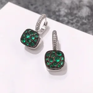 Vue macro de boucles d'oreilles en argent avec pierres émeraude et cristaux en nid d'abeille