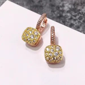 Détail des boucles d'oreilles carrées en nid d'abeille avec pavé de cristaux dorés