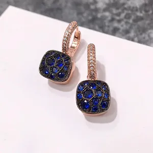 Détail de boucles d'oreilles or rose avec pendentif nid d'abeille noir et cristaux bleus
