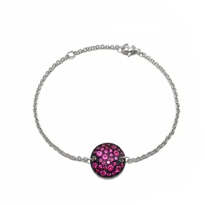 Détail d'un bracelet chaîne argenté avec un pendentif rond serti de zircons roses