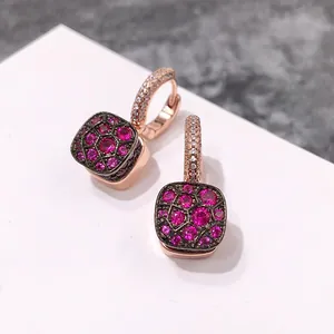 Détail de boucles d'oreilles nid d'abeille en or rose avec zircons roses sur fond