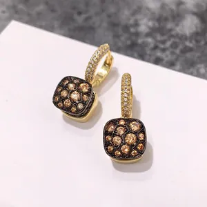 Détail macro de boucles d'oreilles créoles carrées alvéolées avec strass champagne et or