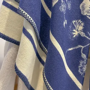 Dettaglio di una sciarpa floreale spessa con bordi blu scuro e cuciture di qualità