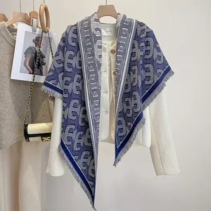 Detail des blau-weißen Jacquard-Schals mit Quastenfransen und Tweed-Jacke mit Goldknöpfen