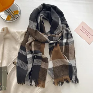 Detailed view of plaid wool blend scarf texture with soft fringe and warm grid pattern