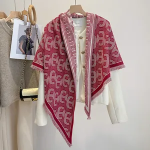 Detailaufnahme des rot-cremefarbenen Kettenschals mit Fransen auf Tweedjacke