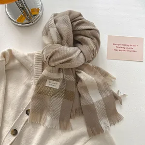 Detailed close-up of wool blend plaid scarf with soft tassels and brand care label