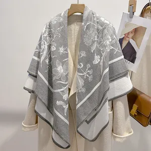 Dettaglio di sciarpa grigia con stampa floreale bianca su cappotto di lana beige