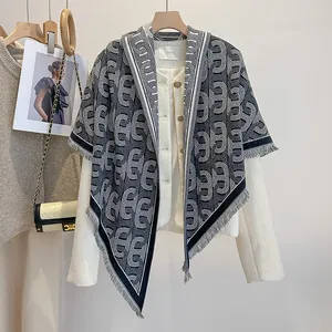 Detail eines weichen schwarz-weißen Schals mit Kettenmuster, Fransen und Goldakzenten