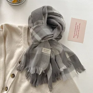 Detail of grey and white plaid wool scarf with classic fringe edges and soft texture