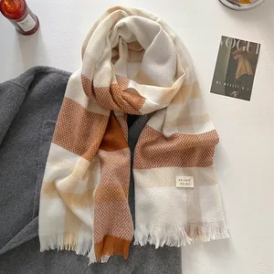 Detail of wool blend plaid scarf featuring soft fringes and a white fabric label