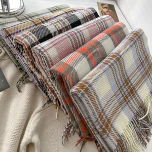 Macro shot of colorful plaid scarves with soft fringe details in autumn winter tones