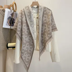 Detail einer weißen Tweedjacke kombiniert mit einem luxuriösen Fransenschal mit Schnallenprint