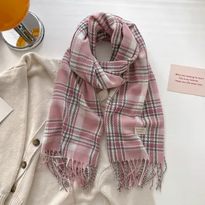 Detail of pink and white checkered scarf with fringe on a warm knit cardigan