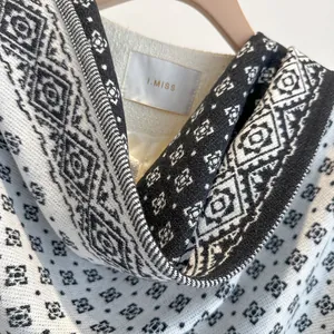 Detailed view of black and white geometric jacquard knit scarf with woven I.MISS label