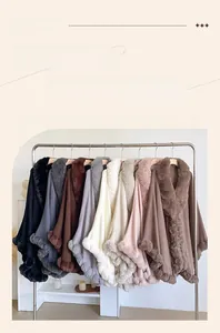 Row of colorful knitted ponchos with faux rabbit fur trim on a silver metal display rack