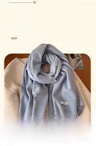Detail of light blue wool scarf showing soft texture, fringe hem and woven label