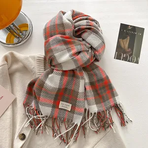 Close-up of orange and brown plaid scarf with fringe details and woven brand label