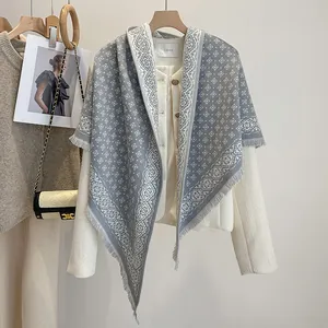 Close-up of grey and white diamond jacquard knit shawl featuring delicate fringe details