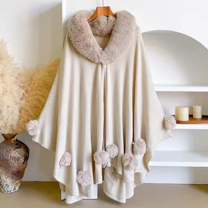 Beige knitted poncho cape with faux rabbit fur collar and soft pompom details